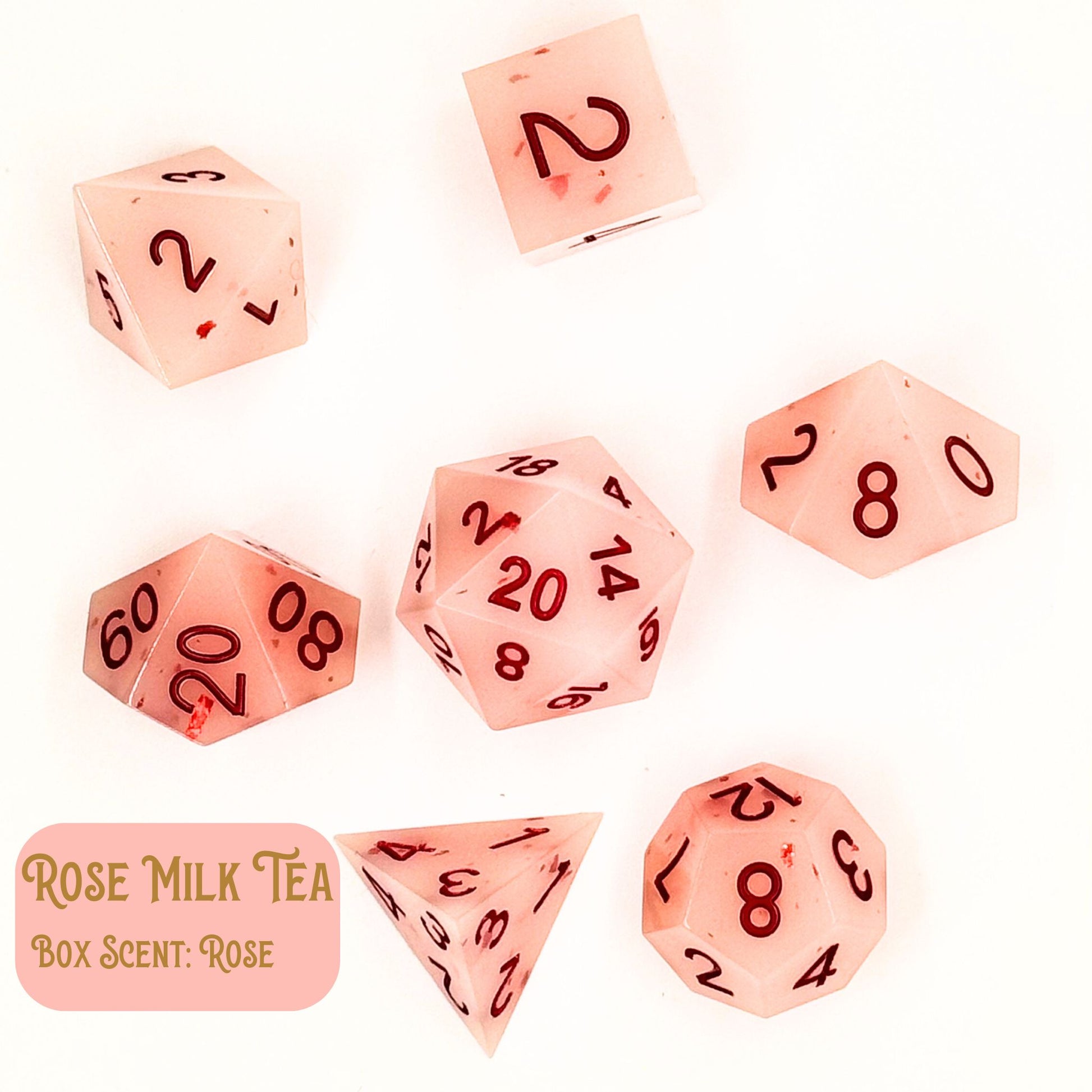 Rose Milk Tea is a collection of seven polyhedral dice with a pink rose tint and reddish numbers. Shown on a white background